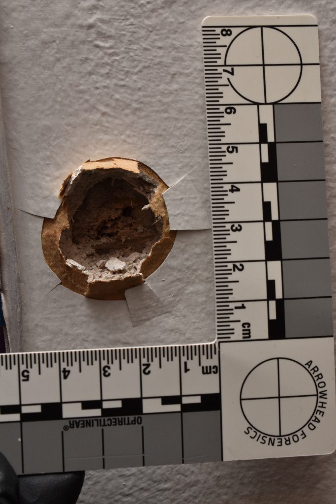 A bullet impact in a surface with a measurement device around it