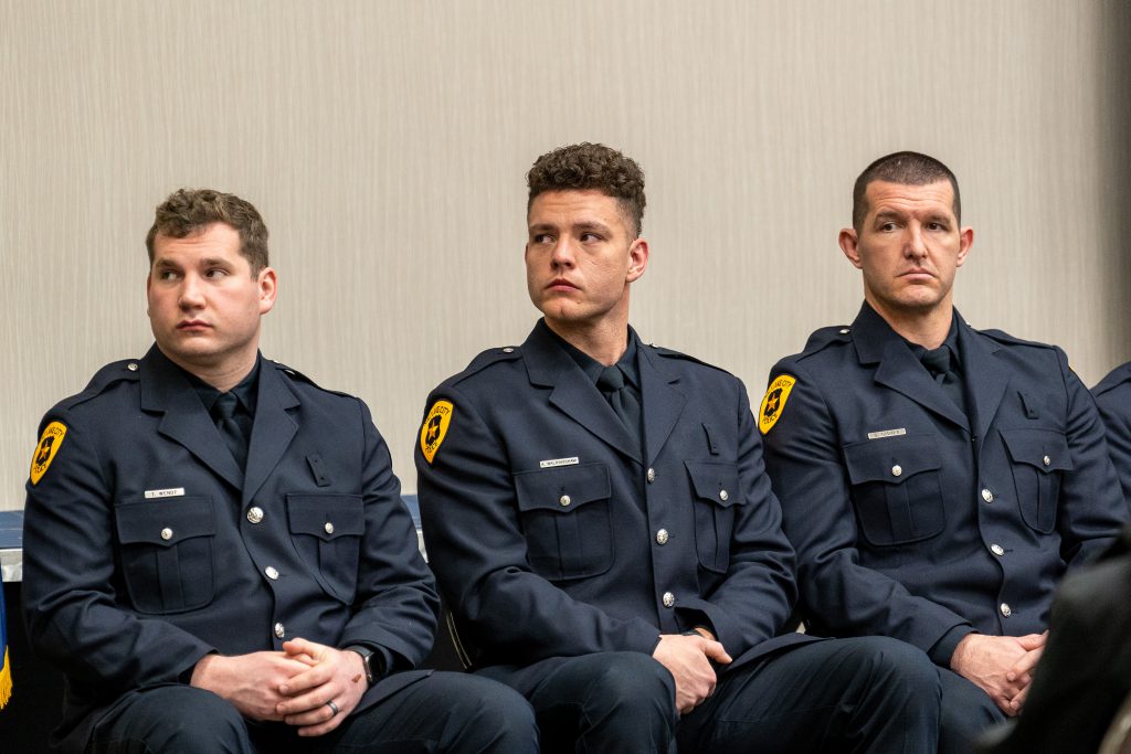 Three newly graduated SLCPD police officers listening to remarks during their graduation ceremony.