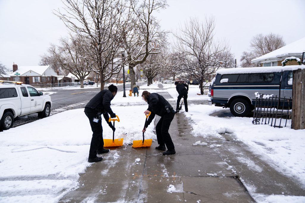 Employees with the Salt Lake City Police Department shovel a sidewalk in Rose Park.