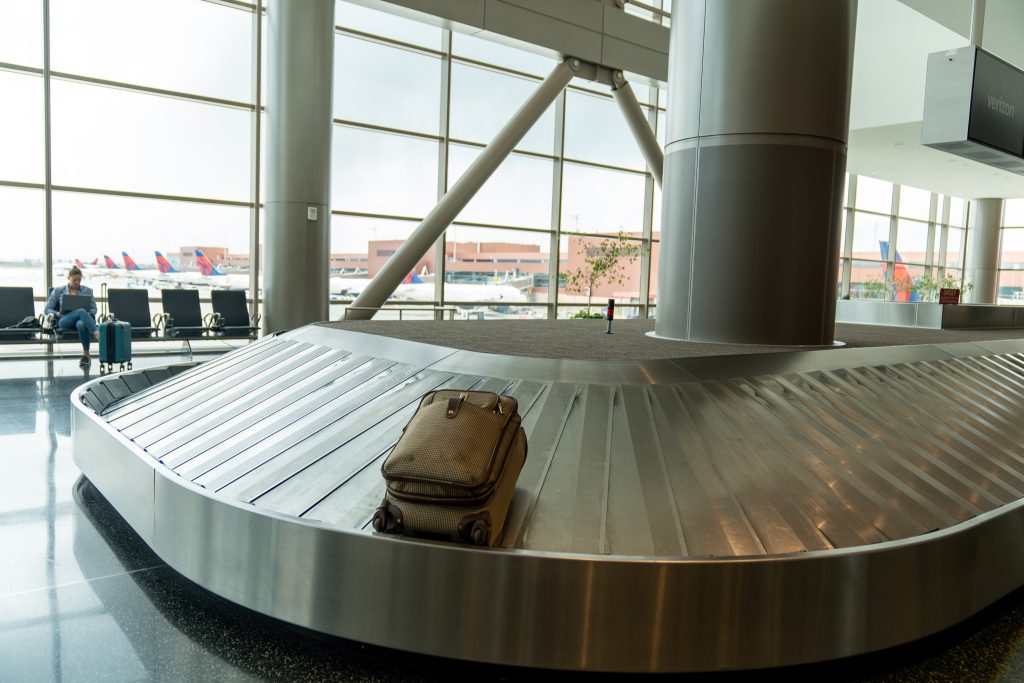 A bag on a baggage claim in an airport setting with planes visible through exterior windows.