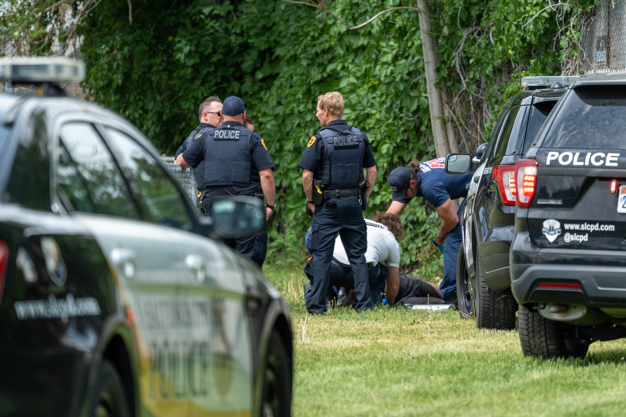 Three Salt Lake City police officers stand by while paramedics assess a man for injuries. (SLCPD | May 24, 2023)