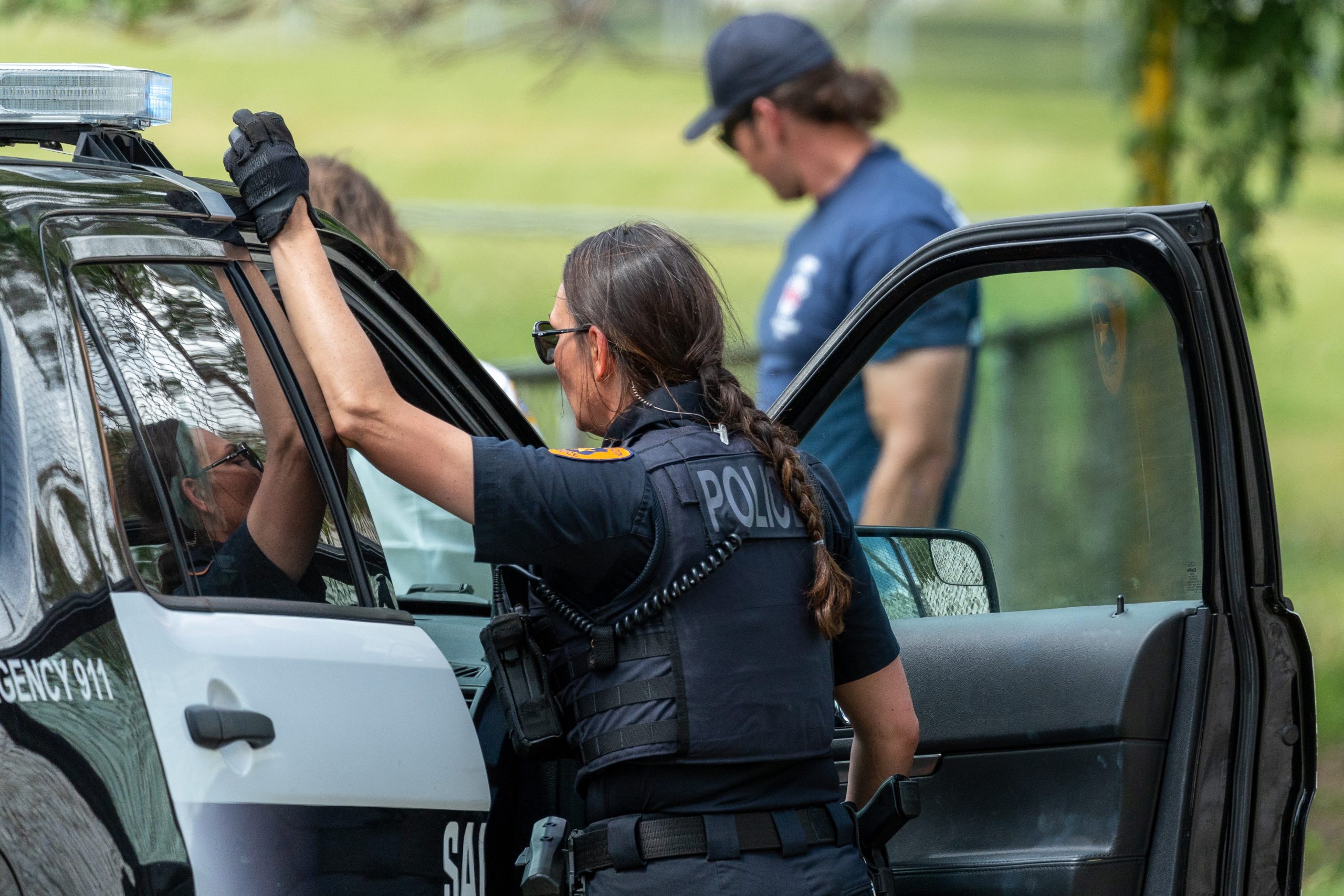 A Salt Lake City police officer talks to another officer sitting inside of a police SUV. (SLCPD | May 24, 2023)