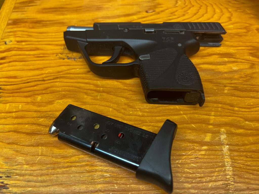 A pistol and loaded magazine laying on a wooden desk