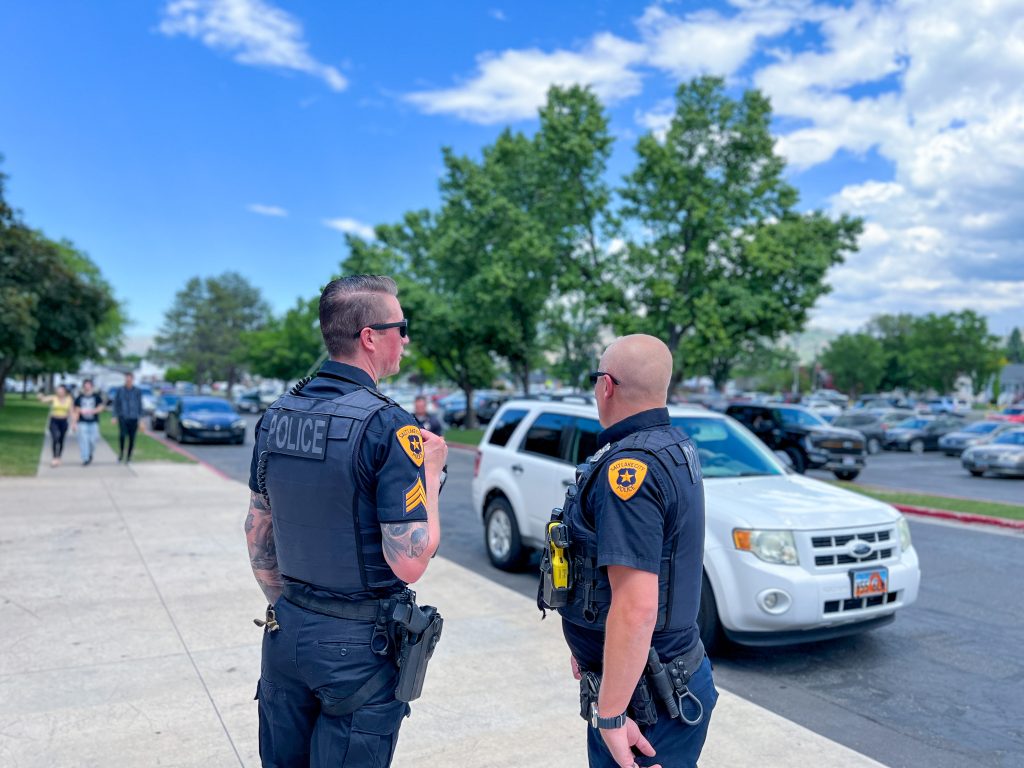 A SLCPD Sergeant speaking with a SLCPD Officer in the parking lot of a school